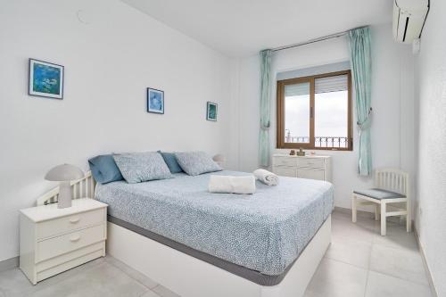 a white bedroom with a bed and a window at Atalaya in Almuñécar