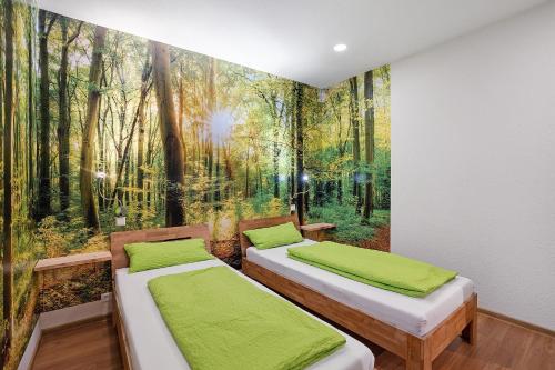 two beds in a room with a mural of a forest at Schwarzwald-Lodge - hundefreundlich in Kappelrodeck