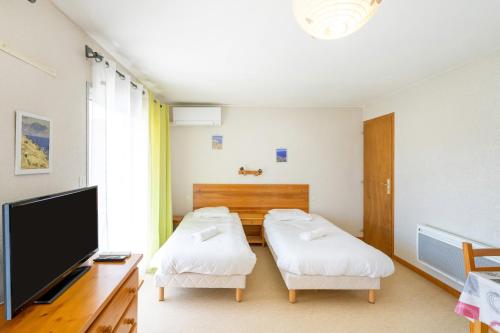 a room with two beds and a flat screen tv at Les Mimosas - Appartement 12 in Cazaubon