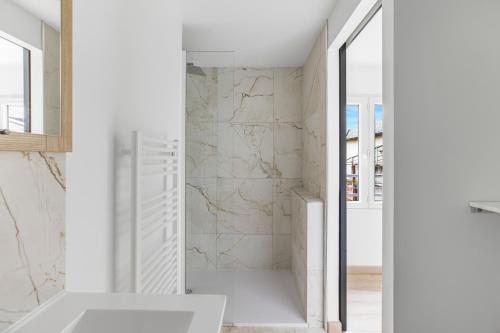 a white bathroom with a shower and a sink at Gîte Brain de nuit in Brain-sur-Allonnes