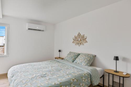 a white bedroom with a bed and two tables at Gîte Brain de nuit in Brain-sur-Allonnes