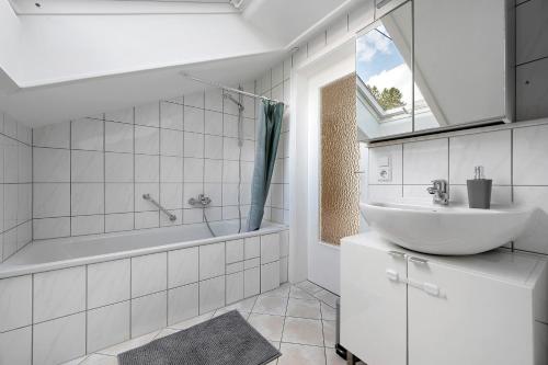 a white bathroom with a sink and a bath tub at Ferienwohnung Kraft in Bad Wildbad