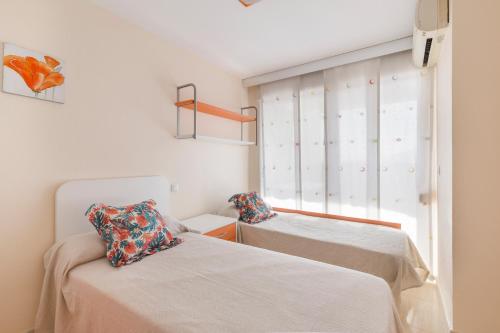 two beds in a room with a window at Apartamento Clayma in Puerto de Mazarrón