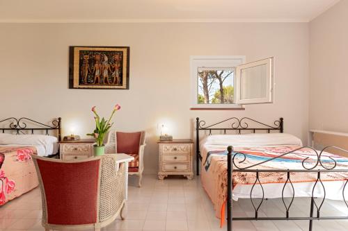 a bedroom with two beds and a table and a window at Villa Magnolie in Chioma