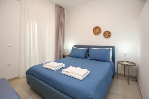 a blue bed with two towels on top of it at Appartamento Ralf - In Centro in Castelsardo