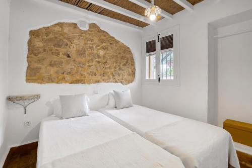 a bedroom with a large bed with white sheets at Araucaria in Denia
