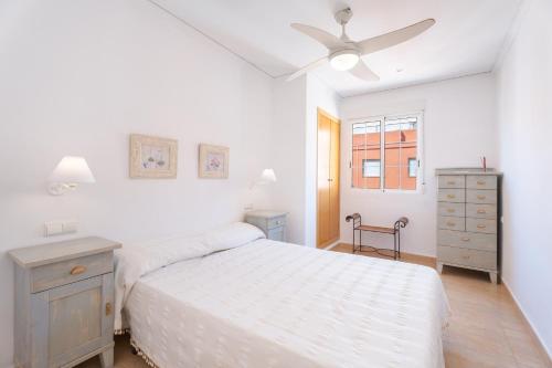 a white bedroom with a bed and a ceiling fan at Mont Pele in Cullera