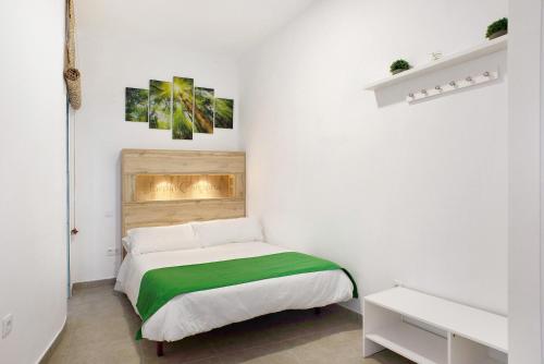 a white bedroom with a bed with a green blanket at Jardin Cardona in Arucas