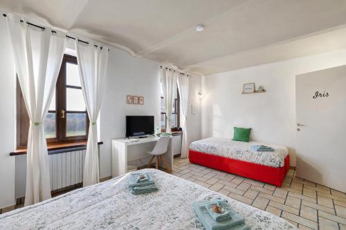 a bedroom with two beds and a desk and a television at B_B La Rugiada in Tigliole