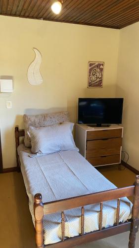 a bedroom with a bed and a flat screen tv at Estúdio Confortável e Completo em Localização Privilegiada in Curitiba