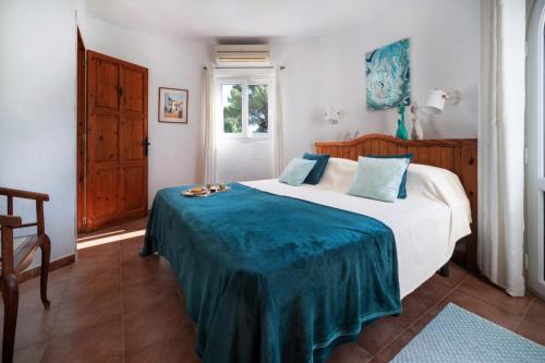 a bedroom with a bed with a blue blanket on it at Villa Torre Xanchu in Sant Josep de sa Talaia