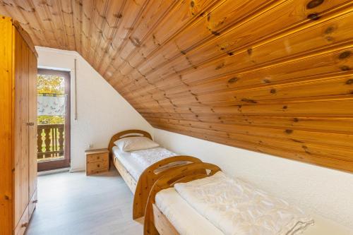 two beds in a room with a wooden ceiling at Landhaus Sophie in Frielendorf