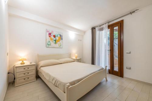 a white bedroom with a bed and a window at Villa Simonetta n9 in Costa Rei
