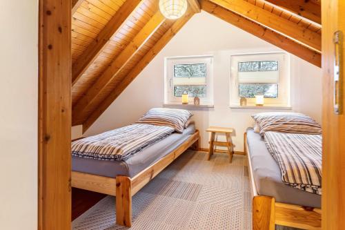 two beds in a attic bedroom with wooden ceilings at Ferienwohnung Am Schleifenbach in Saalfeld