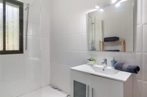 a white bathroom with a sink and a mirror at Casa El Molino in Montecorto