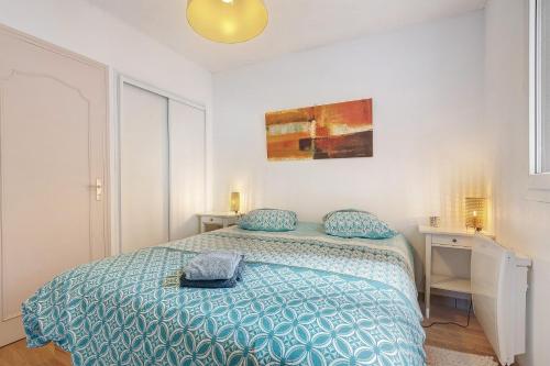 a bedroom with a bed with a blue comforter at Joli appartement quartier artistes in Camaret-sur-Mer