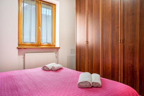 a bedroom with a pink bed with two towels on it at Apartment Villa Irma in Levico Terme