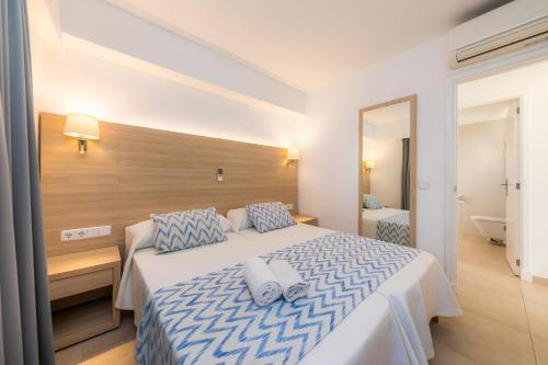 a bedroom with a large bed with blue and white sheets at Apartamento Bon Aire N1 in Cala Ferrera