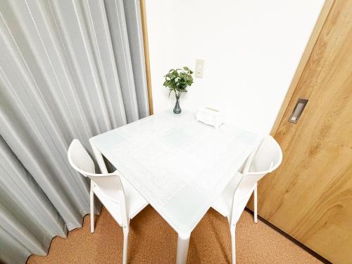 a white table with white chairs and a vase with a plant at 花乃郷 川口 駅徒歩5分 上野 秋葉原 東京直通 池袋 新宿20分圏内 WiFi付き 洋室 温泉施設近く in Kawaguchi