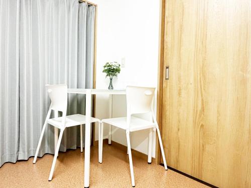 a white table and two chairs in a room at 花乃郷 川口 駅徒歩5分 上野 秋葉原 東京直通 池袋 新宿20分圏内 WiFi付き 洋室 温泉施設近く in Kawaguchi