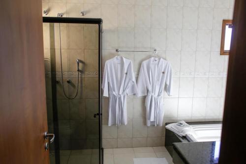 a bathroom with white clothes hanging on a shower at Hotel Abib in Irati
