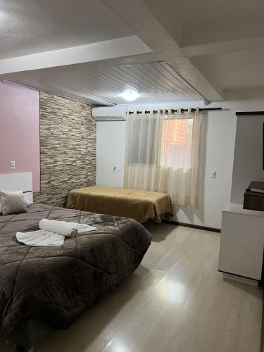 a bedroom with two beds and a brick wall at Pousada Centro in Gramado
