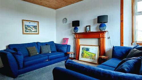 a living room with blue couches and a fireplace at Tigh Stobbian in Lionel