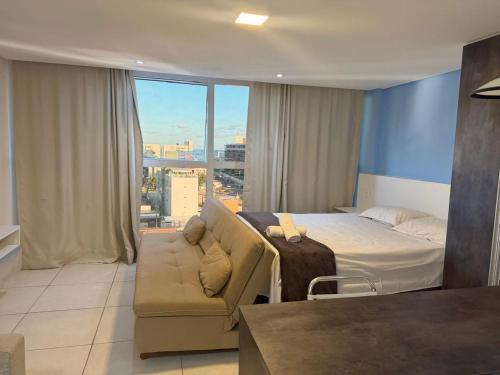 a bedroom with a bed and a couch and a window at Wind Palace Residence in Cabedelo
