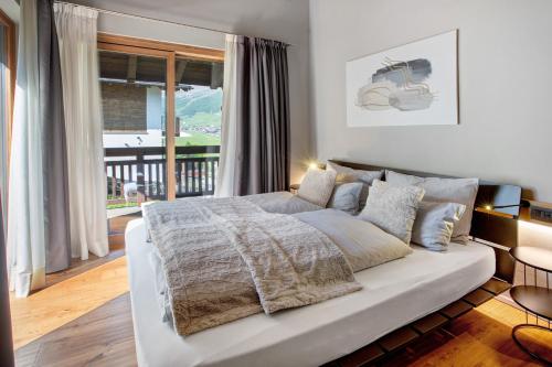 a bedroom with a white bed and a large window at Spark Chalet e Spa Livigno in Livigno