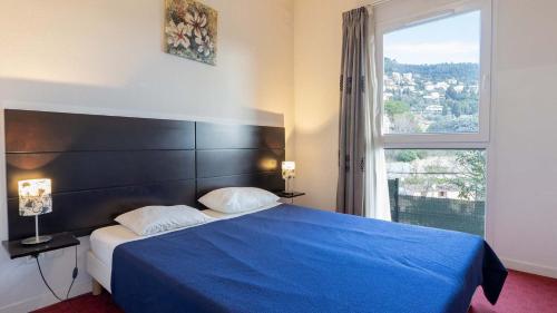 a bedroom with a blue bed with a large window at Virginia N108 - 2P4 in Grasse