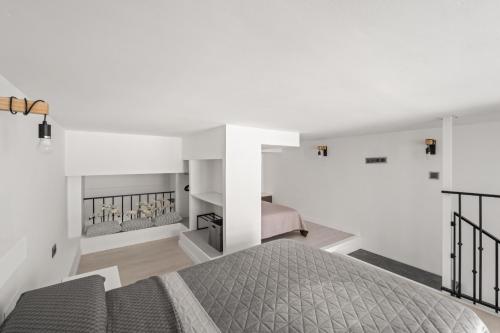a white bedroom with a bed and a staircase at Vima Lofts in Torrevieja
