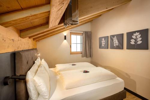 a bedroom with two beds in a room with wooden ceilings at Chalet River Villa Genf Spa - Relax in Livigno