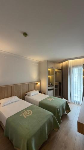 ein Hotelzimmer mit zwei Betten und grünen Decken in der Unterkunft Rıdvan Hotel in Cesme