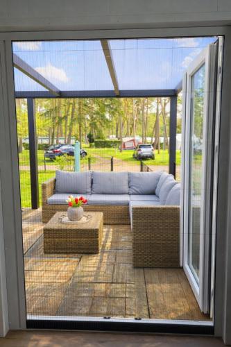 a screened in patio with a couch and a table at Luxe chalet voor gezinnen in familiepark Goolderheide met openlucht zwembaden en ruim overdekt terras 24m2 in Bocholt