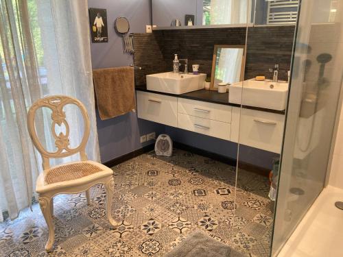 a bathroom with two sinks and a chair and a mirror at Chambre d'hotes La Rambleur in La Teste-de-Buch