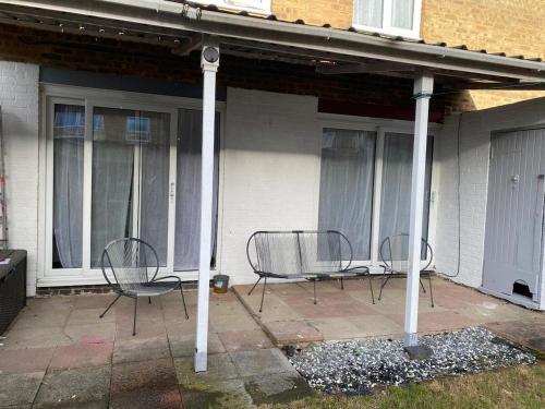 three chairs sitting on a patio in front of a house at 3BR House in Harlow, Essex in Great Parndon