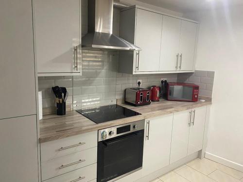 a kitchen with white cabinets and a sink and a microwave at 3BR House in Harlow, Essex in Great Parndon