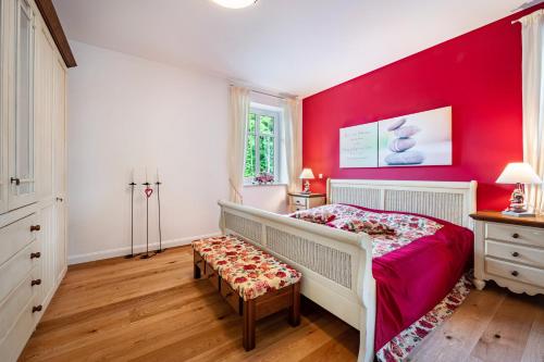 a bedroom with red walls and a bed with a bench at Ferienwohnung Kronsberg mit Sauna in Bösel