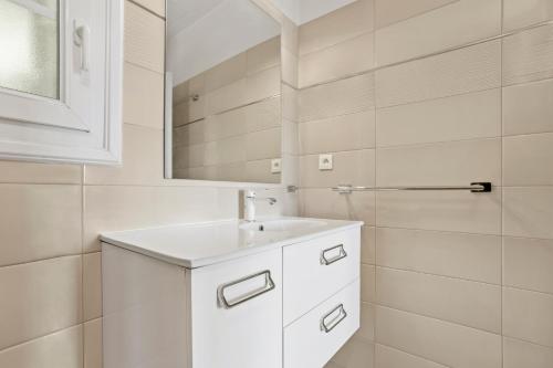 a white bathroom with a sink and a mirror at Studio Palmeraie in Saint-Raphaël