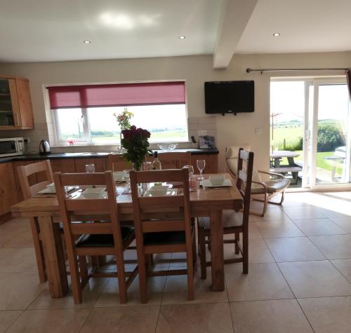 a kitchen and dining room with a wooden table and chairs at Bwthyn Carreg in Aberdaron