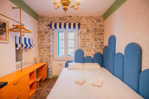a bedroom with a large bed with a blue headboard at Casa Libertà Suites & Studios Piran in Piran