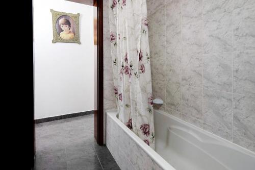 a bathroom with a shower curtain and a bath tub at Casa das Hortênsias in Raminho
