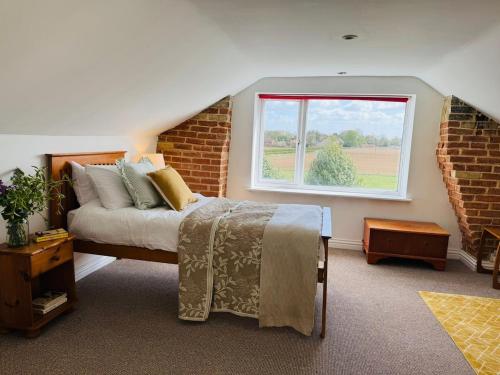 a bedroom with a bed and a window at Meadow Cottage in King's Lynn