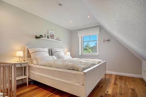 a white bedroom with a bed and a window at Reethaus Meerferien in Poseritz