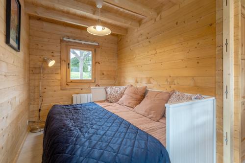 a bedroom with a bed in a wooden cabin at Chalet 5 personnes, proche canal in Landeleau