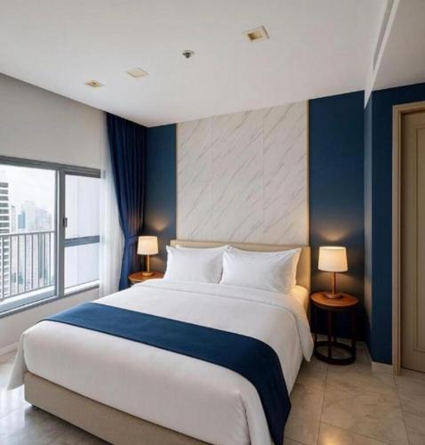 a bedroom with a large bed with a blue wall at Perfect Location Direct Skywalk to BTS Thong in Bangkok