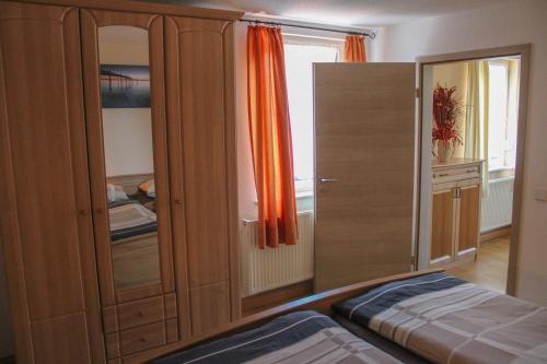 a bedroom with a large wooden cabinet with an orange curtain at Ferienwohnung Haus am Wald in Judenbach