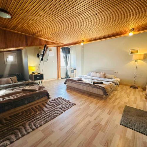a large bedroom with two beds and a wooden ceiling at JD Maisonette for 4 in Neoi Epivates