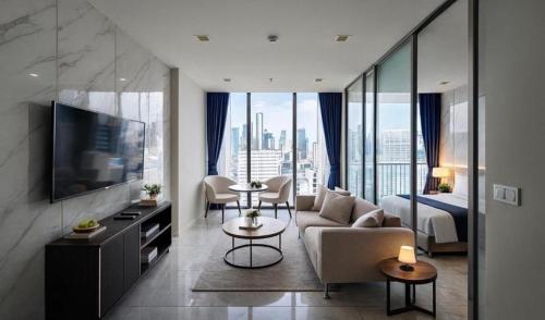 a living room with a couch and a tv and a bed at Perfect Location Direct Skywalk to BTS Thong in Bangkok