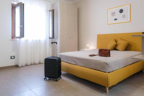 a bedroom with a yellow bed and a suitcase at Domus del Gotha in Mazzarino